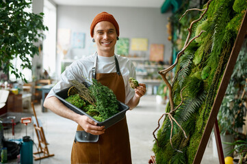 Portrait of young hipster florist standing at creative floral composition