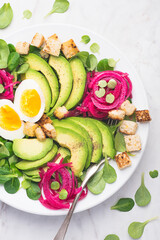 Light summer or spring salad with vegetable fats and protein, vegan meat alternative. Balanced food. Avocado, valyrian salad, egg, pickled onion in beetroot. Healthy dinner, lunch. Top view