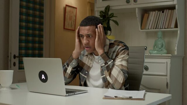 Man reads bad news using laptop. Upset African American man is nervous about something looking at commputer.