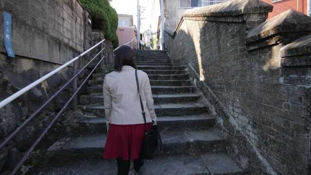 Back shot of asian girl walking up the historical stone stairs in Nagasaki Japan.