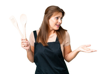 Middle age caucasian woman holding a rolling pin over isolated background with surprise expression...