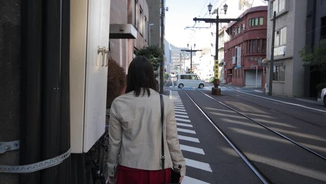 Back shot of asian girl walking by the railway in Nagasaki Japan.