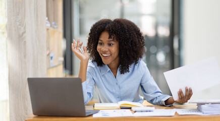 Beautiful asian african business woman make a video conference by laptop computer and sitting at office desk,