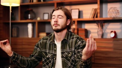 Funny scene of young bearded man meditating breathes slowly and eating popcorn in the living room with warm sunset light. Relaxed guy practice with online yoga course at home. Comic frame.