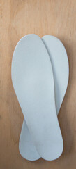 Insoles on old wooden board. Prevention of orthopedic foot diseases, foot care. Rustic background. Top view.
