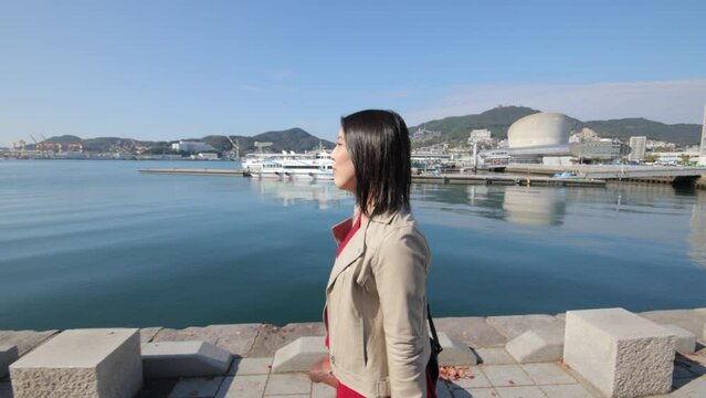 Asian woman walks the wharf by herself. Autumn. Nagasaki, Japan.