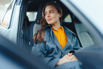 Excited young woman sitting in her car, waiting for somebody. - obrazy, fototapety, plakaty