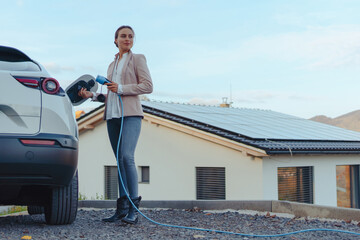 Young woman charging her electric car in home, sustainable and economic transportation concept.