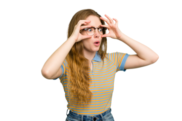 Young caucasian redhead woman isolated keeping eyes opened to find a success opportunity.