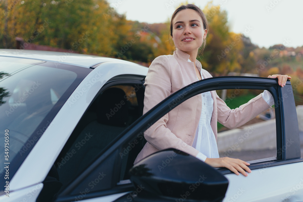 Wall mural happy young woman getting out of her car.