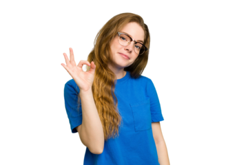Young caucasian redhead woman isolated winks an eye and holds an okay gesture with hand.