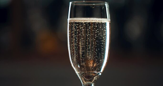 Party, celebration and bubbles in glass of champagne on dark background for social event, holiday and anniversary. Festival, birthday and zoom of fizz in alcohol drink in flute to celebrate birthday