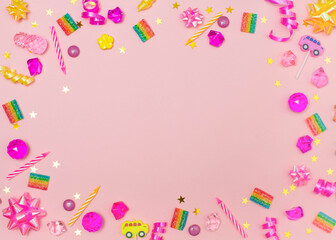 Children birthday party background with candels sweets cristals ribbons and confetti over pink background.