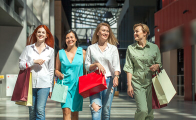 Four happy middle aged women walking in the mall