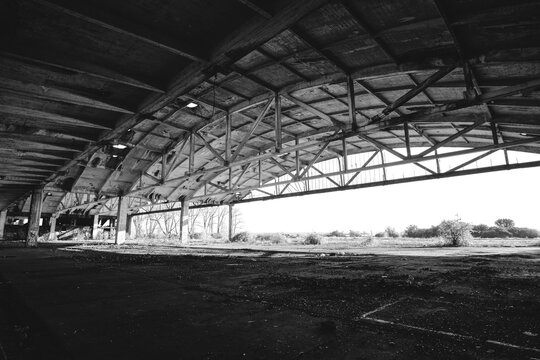 Metal structures old, abandoned aircraft hangar in black and white photo.