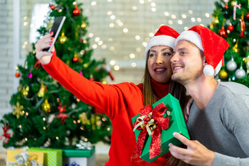 A young couple is celebrating their Christmas together happily at home.