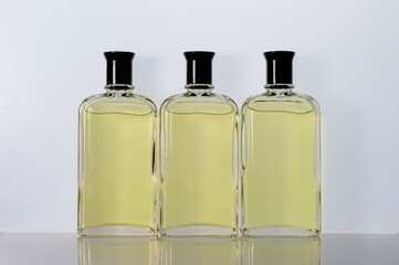 Transparent, glass jars with perfume liquid stand on a white surface