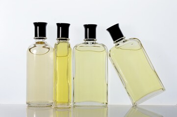 Transparent, glass jars with perfume liquid stand on a white surface