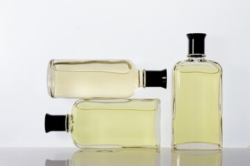 Transparent, glass jars with perfume liquid stand on a white surface