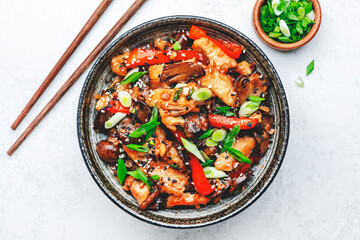 Stir fry with turkey fillet, red paprika, mushrooms, green chives and sesame seeds in bowl Asian cuisine dish. White kitchen table background, top view