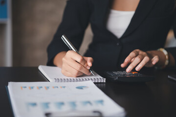 Businessman using a calculator to calculate numbers on a company's financial documents, he is analyzing historical financial data to plan how to grow the company. Financial concept.