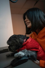 a long-haired puppy and his short-haired, brown-haired owner use the mouse. He is adorable and wearing a warm colored coat.