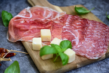 Slices Of  Traditional Italian antipasti mortadella Bolognese,salame Milano, parmesan cheese  and prosciutto crudo   on a wooden  cutting board.