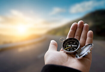Traveler explorer man holding compass in a hand in mountains at sunrise, point of view. © login2002