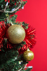 Golden Christmas toys on a Christmas tree on a red background. Merry christmas and new year concept