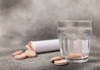 Effervescent tablet in a glass of water on a black textured background. Vitamins. Health concept....