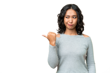 Young Argentinian woman over isolated background unhappy and pointing to the side