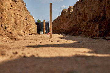 Installation of water supply in the city.A trench was prepared for laying water pipes, with wooden stakes to indicate the direction and a concrete well covered with waterproofing mastic.