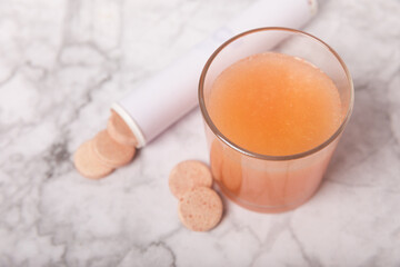 Effervescent tablet in a glass of water on a white marble background. Vitamins. Health concept. Immunity drug. Space for copy. Space for text.