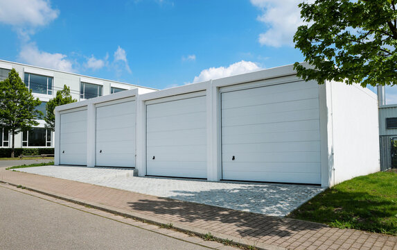 Four modern white free standing garages with sectional door with modern architecture in summe