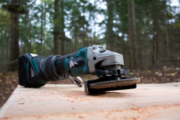 low perspective close up battery powered sander. Wood worker tool on wooddeck in outdoor forest scene. Craftsman equipment for construction. 