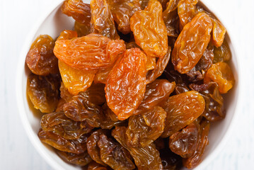raisins at porcelain bowl, white wood table