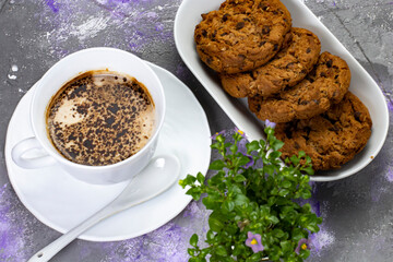 Cup with coffee and chocolate and oatmeal cookies on an abstract background, close-up, selective focus