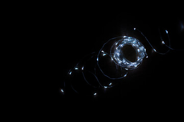 Thin garland with beautiful lights on black closeup
