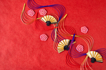 日本の正月イメージ------波型水引と梅型水引と扇（赤い和紙の背景）	