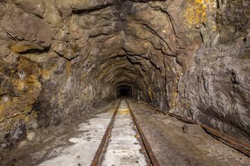 Underground abandoned gold iron ore mine shaft tunnel gallery passage with rails