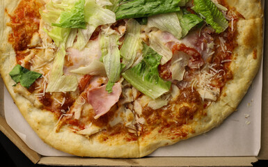 juicy tasty fragrant pizza with greens sausage and cheese in a cardboard box close-up. for labels, splash screens, signage