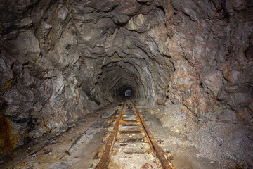 Underground abandoned gold iron ore mine shaft tunnel gallery passage with rails