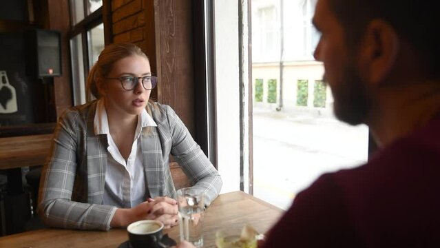 Two business people from different companies dating and hiding in cafeteria so colleagues cant see them together. Businesspeople date night drinking coffee and tea sitting in the bar.