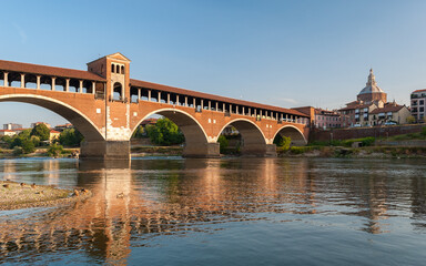 Skyline of Pavia with Ponte Coperto reflecting over the river Ticino in northern Italy