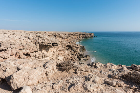 Top view from cliff of a wild beach with clear blue sky at the coat of Ras Al Jinz, Sultanate of Oman.