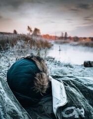 Vertical shot of a sleeping person wearing a winter jacket in a sleeping bag