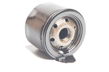 Car oil filter with a puddle of engine oil isolated on white background