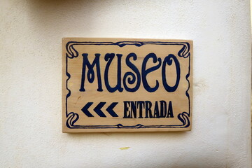 Museo Entrada. (Musée. Entrée.) Plaque en céramique indiquant la direction de l'entrée d'un musée. Texte en espagnol. 