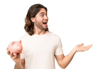 Young handsome man holding a piggybank over isolated background with surprise facial expression