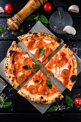 Neapolitan pepperoni pizza with mozzarella, tomato sauce, spinach on a thick dough cut into pieces from the oven.